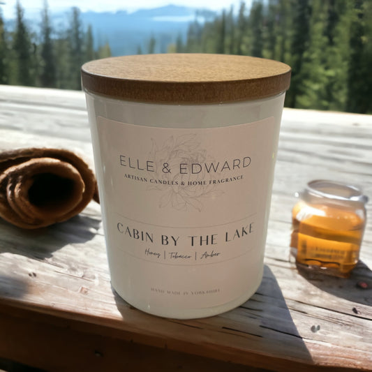 A candle on a ledge of a wooden lodge overlooking the forest and lake 